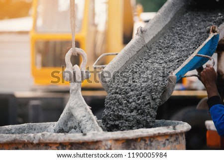Industrial construction machinery workers pouring cement concrete using a concrete bucket