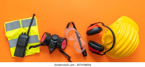 Industrial Construction Site Worker Health And Safety Concept. Work Wear Protection Equipment On Orange Color Background, Personal Protective Gear, Top View.