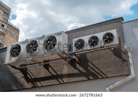 Industrial cooling units with big ventilation fans installed on an urban structure. Selective focus.