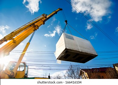 Industrial Crane operating and lifting an electric generator against sunlight and blue sky