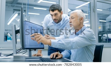 Industrial Designer Has Conversation with Senior Engineer While Working in CAD Program, Designing New Component. He Works on Personal Computer with Two Monitors.