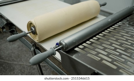 Industrial dough sheeter rolling dough in a bakery. - Powered by Shutterstock