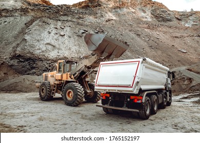 Industrial dumper trucks and wheel loader bulldozer working on highway construction site, loading and unloading gravel and earth. heavy duty machinery activity