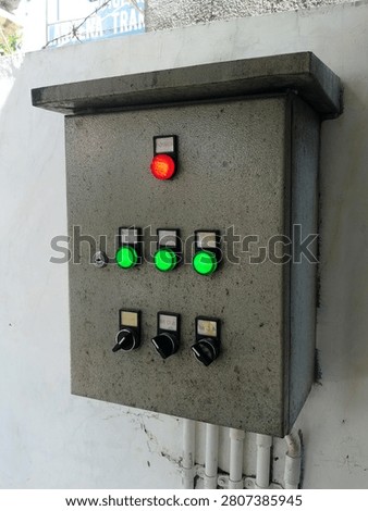 Industrial electrical control panel with illuminated indicator lights and selector switches mounted on a wall, used for monitoring and controlling electrical equipment and machinery.