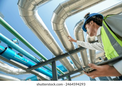 Industrial engineer adjusting pipeline valve with radio communication on construction site. Engineer on urban construction site using radio to coordinate with team on a sunny industrial rooftop. - Powered by Shutterstock