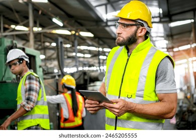 Industrial engineer with helmet and safety vest holds tablet for checking process and machinery machine engine at manufacturing factory. Worker man with safety glasses works in industry workplace. - Powered by Shutterstock