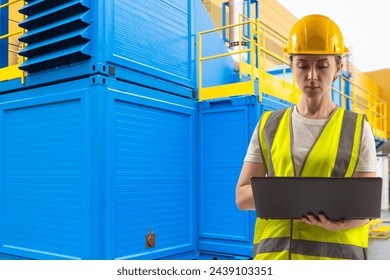 Industrial Engineer in Safety Gear Analyzing Data on Laptop at Electrical Substation - Powered by Shutterstock