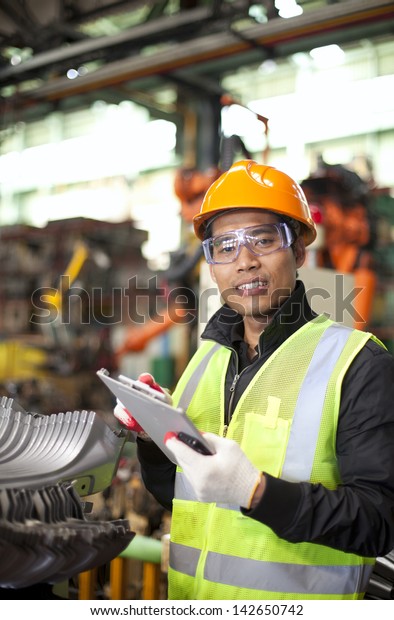 industrial engineer taking notes in factory\
vertical image