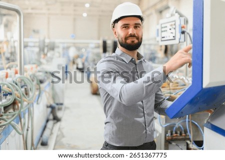 Industrial engineer wearing hardhat operating machinery in a modern factory, showcasing expertise and advanced technology