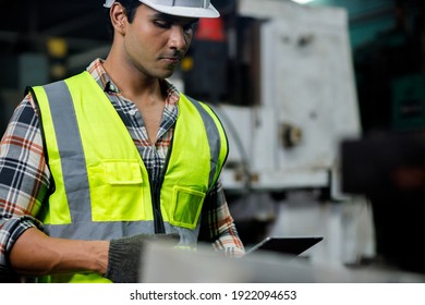Industrial engineer who wearing hard hat, safety vest and gloves is using touchscreen tablet to open the machine checklist at the heavy industry manufacturing factory. - Shutterstock ID 1922094653