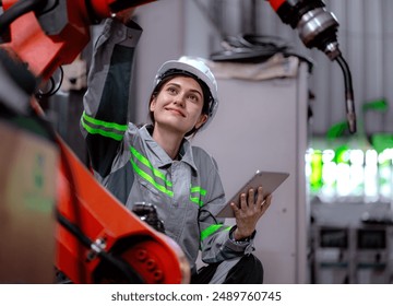 Industrial engineer woman working on robot arm maintenance in modern technology factory. Technician checking robotic automated welding torch machine to control welding process.Innovative engineering. - Powered by Shutterstock