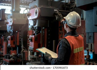 Industrial engineer worker wearing helmet and safe glasses, checking machinery and holding chart board, work at manufacturing plant factory, working with machine in industry concept