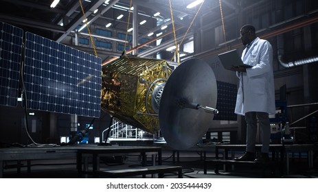 Industrial Engineer Working On Artificial Satellite Construction. Aerospace Agency: African American Scientist Using Tablet Computer To Develop Spacecraft For Space Exploration And Data Communication.