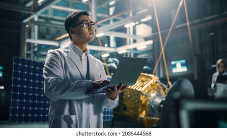 Industrial Engineer Working On Artificial Satellite Construction. Aerospace Agency: Asian Scientist Using Laptop Computer To Develop Spacecraft For Space Exploration And Data Communication.