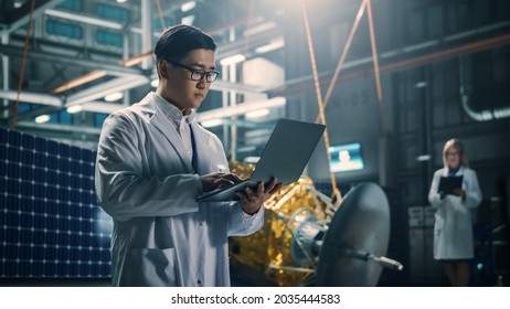 Industrial Engineer Working On Artificial Satellite Construction. Aerospace Agency: Asian Scientist Using Laptop Computer To Develop Spacecraft For Space Exploration And Data Communication.