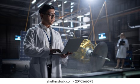 Industrial Engineer Working On Artificial Satellite Construction. Aerospace Agency: Asian Scientist Using Laptop Computer To Develop Spacecraft For Space Exploration And Data Communication.