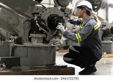 Industrial engineer working on robot maintenance in AI futuristic electronic technology factory. Female technician checking automated robotic machine. Modern smart woman empowerment in industry 4.0. - Powered by Shutterstock