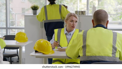 Industrial engineers sitting in canteen and talking on lunch break. Construction company workers in safety uniform eating meal and chatting in modern office
