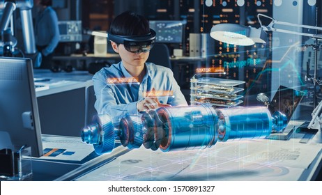 Industrial Factory Chief Engineer Wearing AR Headset Designs a Prototype of an Electric Motor on the Holographic Projection Blueprint. Futuristic Virtual Design of Mixed Technology Application.