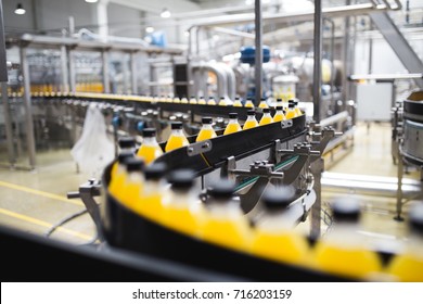 Industrial factory indoors and machinery. Robotic factory line for processing and bottling of soda and orange juice bottles. Selective focus. Short depth of field. - Shutterstock ID 716203159