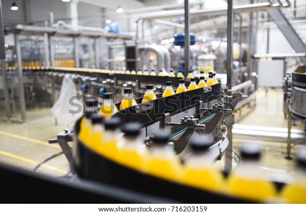 Industrial factory indoors and
machinery. Robotic factory line for processing and bottling of soda
and orange juice bottles. Selective focus. Short depth of
field.