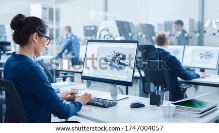 Industrial female Engineer Working on a Personal Computer, Screen Shows CAD Software with 3D Prototype of Electric Engine. In Background Modern Factory with High-Tech CNC Machinery