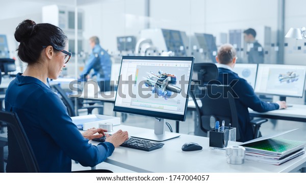 Industrial female\
Engineer Working on a Personal Computer, Screen Shows CAD Software\
with 3D Prototype of Electric Engine. In Background Modern Factory\
with High-Tech CNC\
Machinery