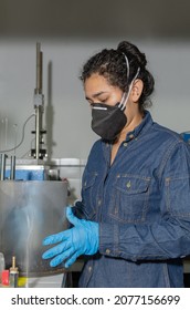 Industrial female worker with protective mask and latex gloves, testing asphalt in geological laboratory