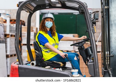 Industrial Female Worker Wearing A Medical Mask Using A Forklift In A Warehouse