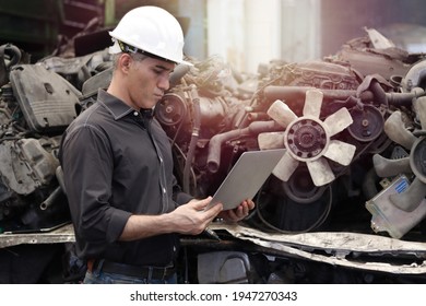 Industrial Foreman Worker Wearing Helmet Using A Laptop Computer At Manufacturing Plant Factory Industry, Senior Male Engineer With Many Engine Parts As Blurred Background