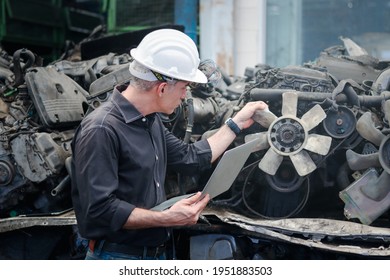 Industrial Foreman Worker Wearing Helmet Using A Laptop Computer At Manufacturing Plant Factory Industry, Senior Male Engineer With Many Engine Parts As Blurred Background