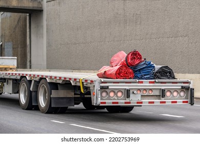 Industrial Grade Big Rig Long Haul Semi Truck Transporting Rolled Up Cover Tarps On Step Down Semi Trailer Driving On The Multiline Highway Road With Another Traffic