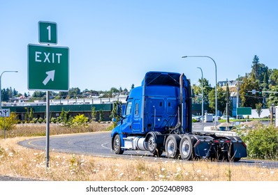 Industrial Grade Powerful Big Rig Blue Bonnet Semi Truck Tractor With Five Wheel Turning On The Highway Exit Running To Warehouse For Pick Up Loaded Semi Trailer For The Next Freight