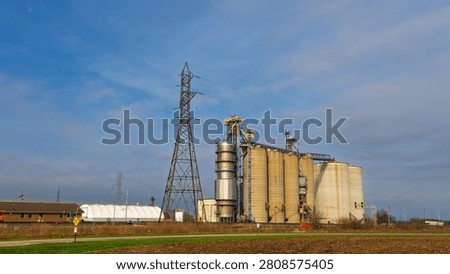 Industrial grain elevator with silos and power lines under a blue sky