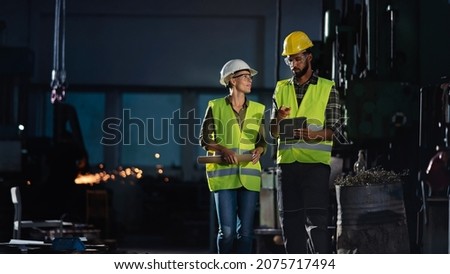 Industrial inspectors doing a general check up indoors at metal workshop.