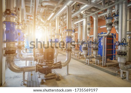 Industrial interior chiller and boiler system room of equipment heating, pipelines, water pump, valves and manometers system at the large building in factory