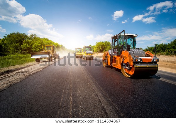 industrial\
landscape with rollers that rolls a new asphalt in the roadway.\
Repair, complicated transport\
movement.