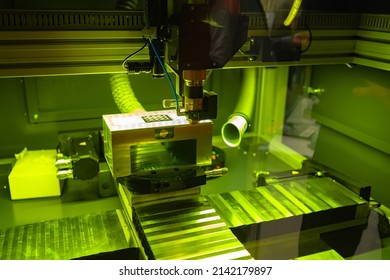 Industrial laser equipment close-up. Camera with a laser machine. Laser machine chamber behind transparent glass. Industrial equipment is illuminated in neon green. Engraving equipment