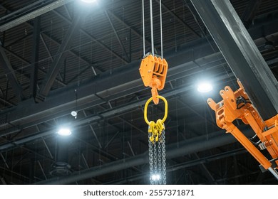 Industrial lifting equipment. Winch hook at moment of lifting chains. Equipment for moving cargo around hangar. Industrial winch on metal beam. Industrial building with orange winch - Powered by Shutterstock