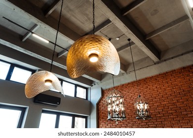 The industrial loft features artistic hanging lamps, woven design, exposed brick walls, and large windows, creating a stylish and contemporary ambiance with a modern and trendy feel - Powered by Shutterstock