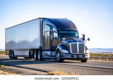 Industrial long hauler big rig black semi truck tractor with truck driver sleeping compartment transporting cargo in dry van semi trailer driving on the straight wide highway road in California - Shutterstock ID 2253269511