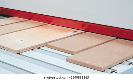 An industrial machine in a factory cuts and applies patterns to wooden panels for furniture production - Powered by Shutterstock