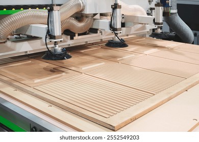 An industrial machine in a factory cuts and applies patterns to wooden panels for furniture production - Powered by Shutterstock