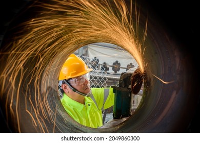 An industrial man who cuts a lot of sparking steel pipe is skilled at grinding steel and metal parts, applies electric grinding wheels to industrial steel structures. - Powered by Shutterstock