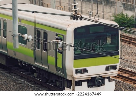Industrial or mass transit background featuring detail of electrical railroad with local suburban train, rails and contact lines illustrating modern urban public transport concept, Tokyo, Japan.