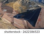 Industrial mine waste dam (tailing dam). A tailings dam is typically an earth-fill embankment dam used to store byproducts of mining operations after separating the ore from the gangue.	
