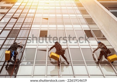 Industrial mountaineer laborers hangs on wall cityscape building. Rope access workers on residential house, washing exterior facade glazing. Industry urban works concept. Copy advertising text space