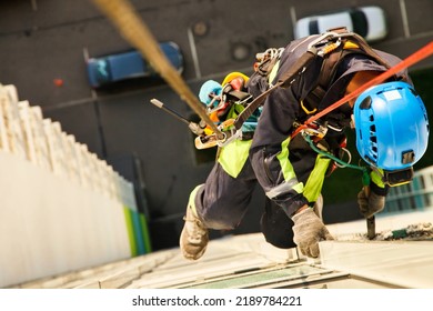 Industrial mountaineering worker hangs over residential facade building during high rise cleaning work. Rope access laborer hangs on wall of house. Concept of industry urban works. Copy space