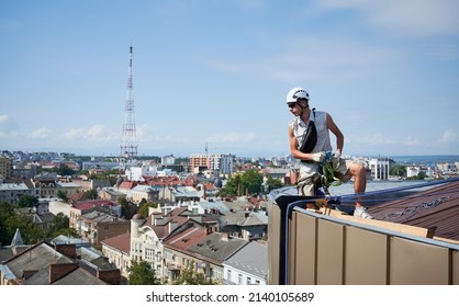 Industrial Mountaineering Workers Washing Glass Windows Of High-rise Building. Alpinist Working With Climbing Ropes On The Roof Of Skyscraper.