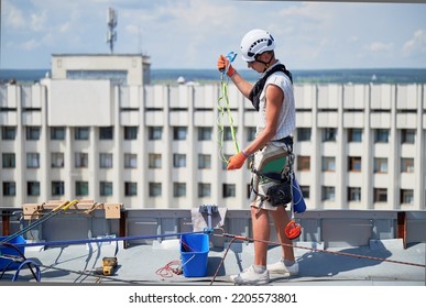 Industrial Mountaineering Workers Washing Glass Windows Of High-rise Building, Working With Climbing Ropes On The Roof Of Skyscraper.